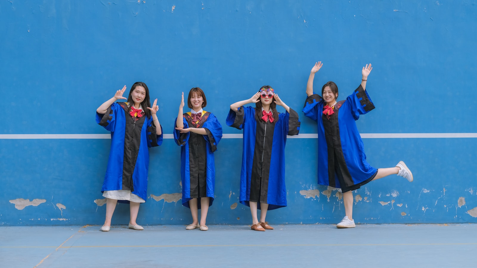 a group of girls in black and white dresses in front of a blue wall