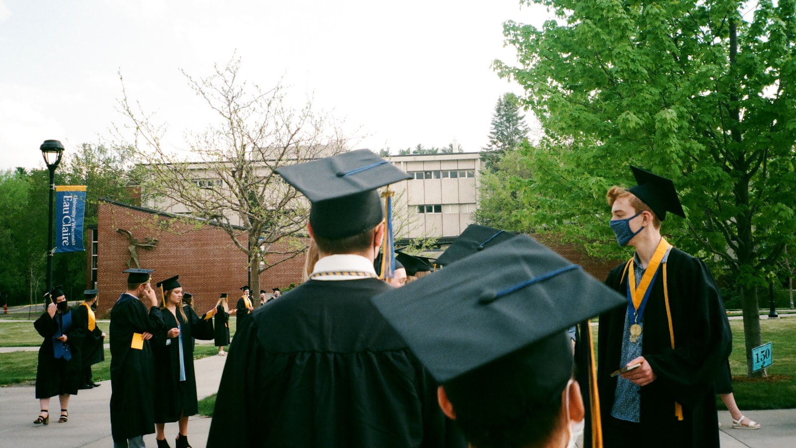 people in academic dress standing near green trees during daytime