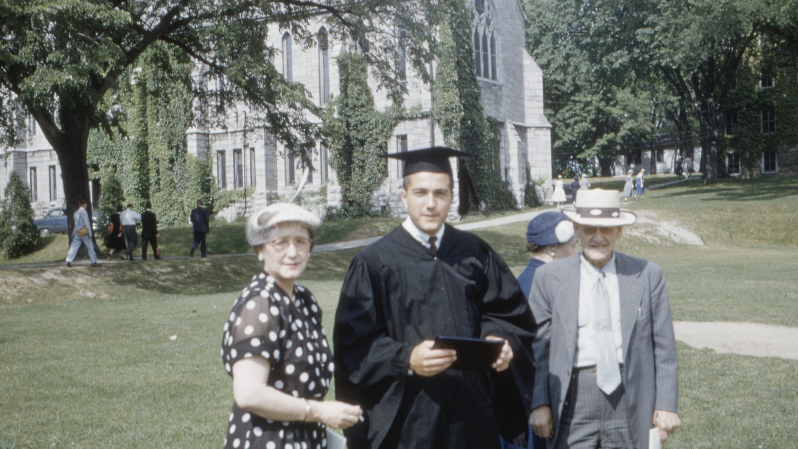 man wearing academic suit standing beside man and woman