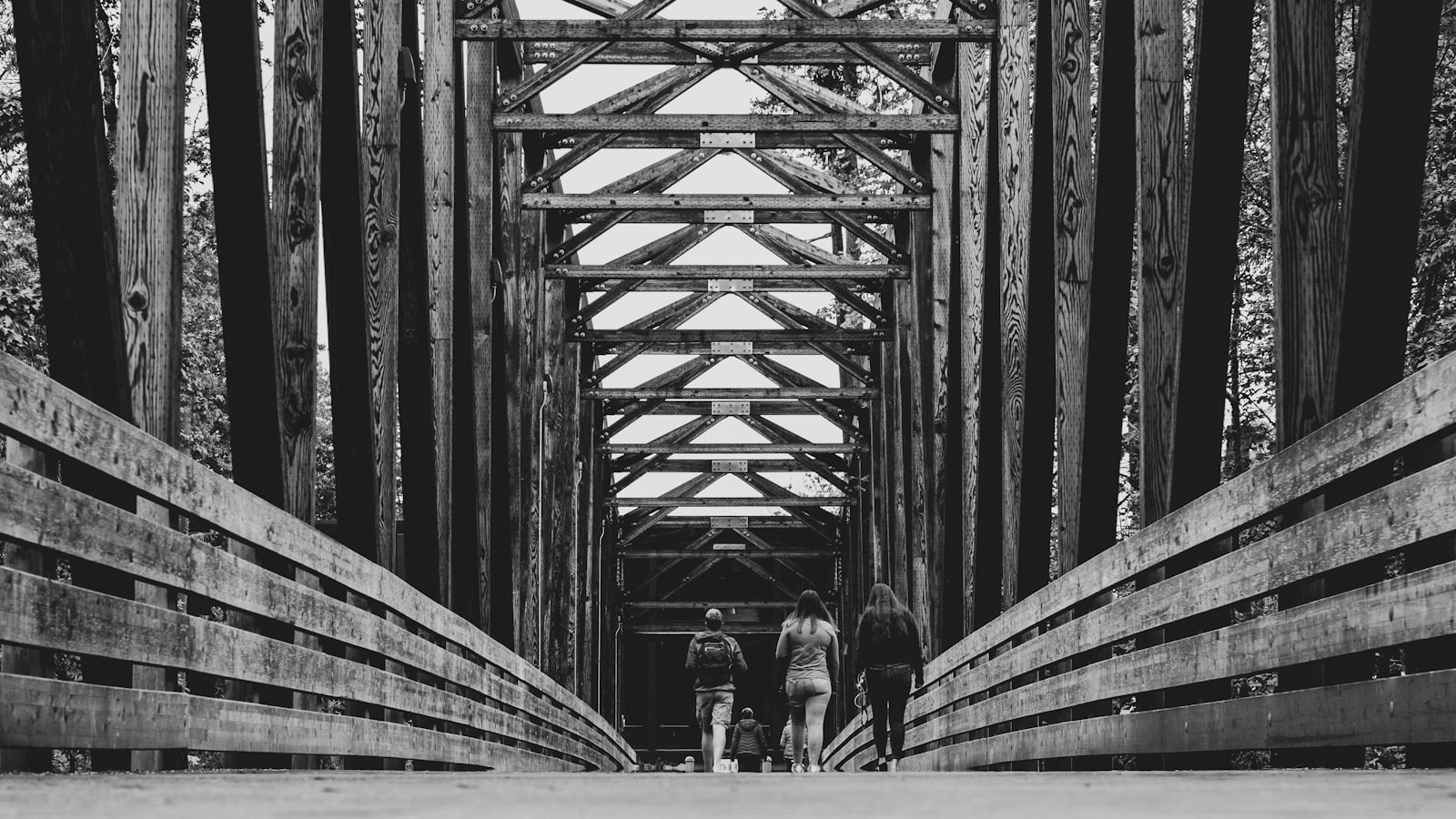 grayscale photography of people walking on bridge