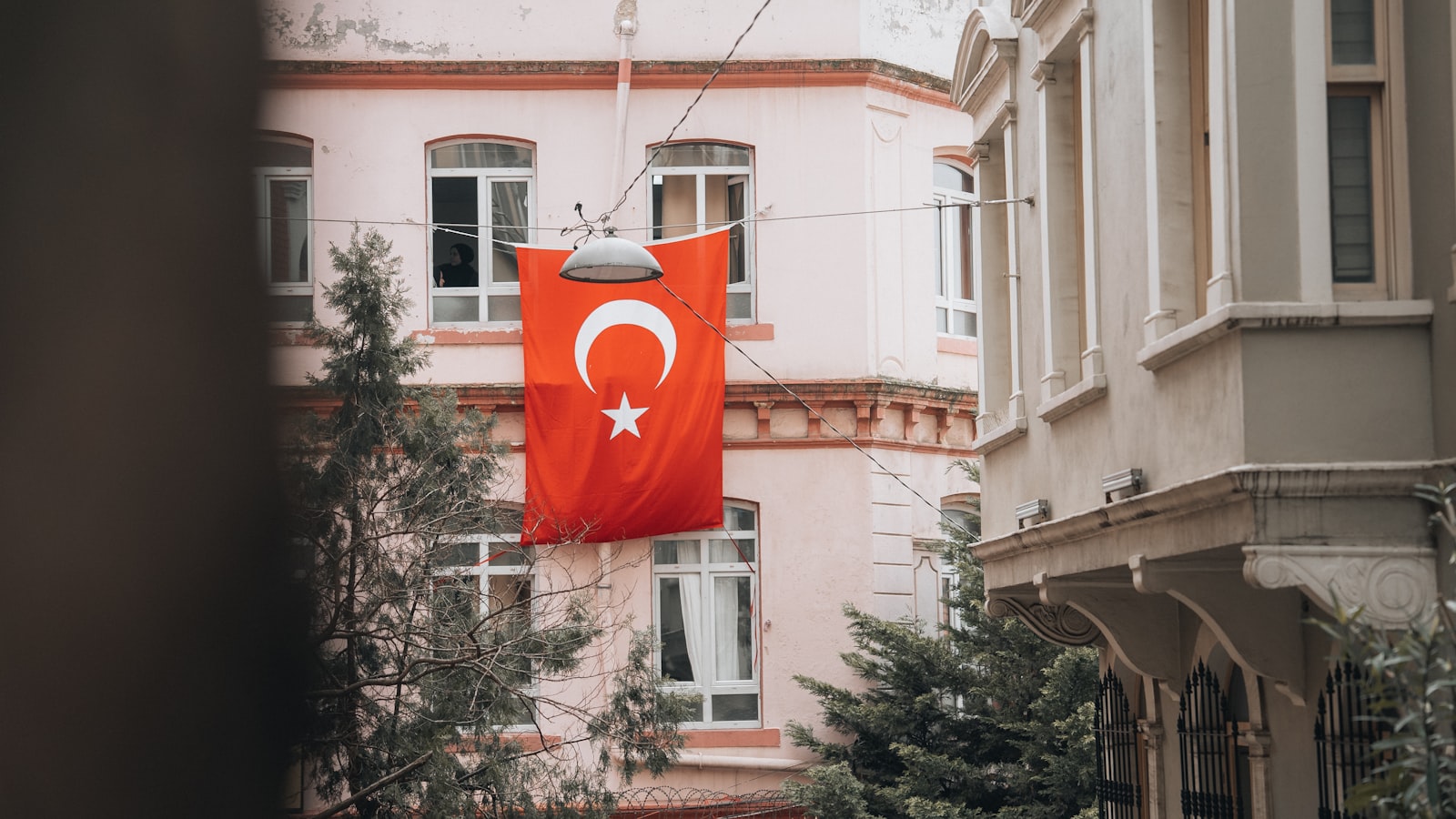 a red flag hanging from a building next to a tree