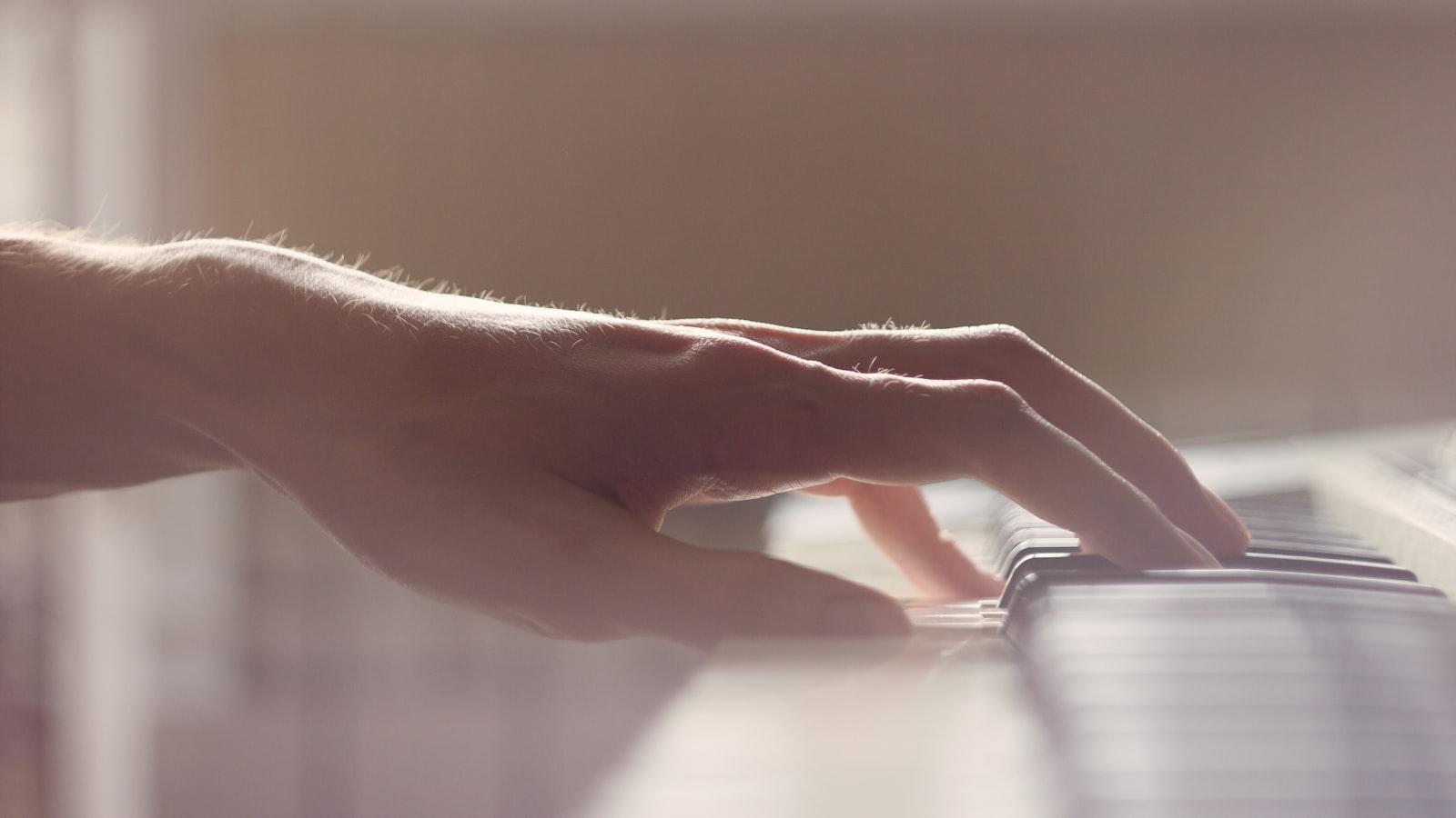 A hand plays the piano keys.