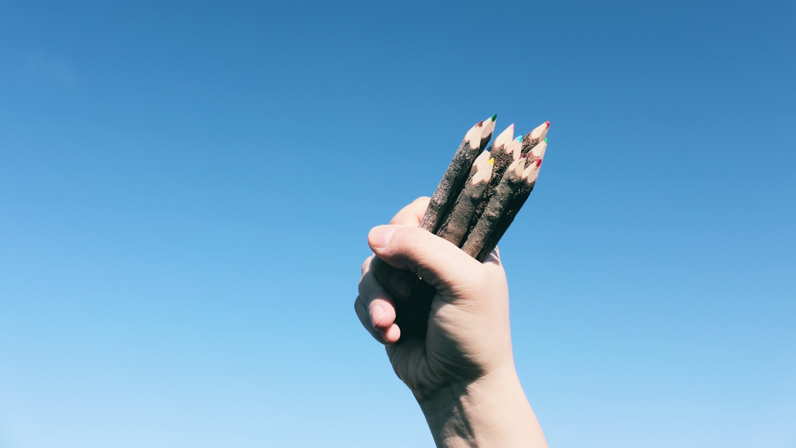 person holding brown wooden pencils