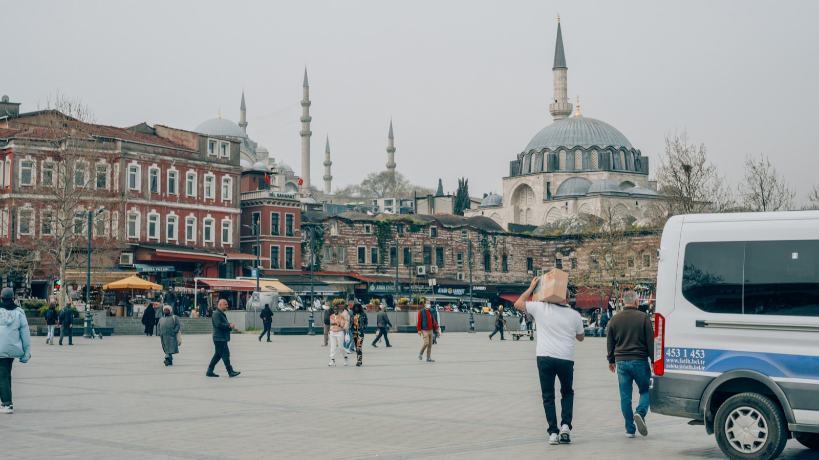 a group of people walking in a plaza with buildings in the background