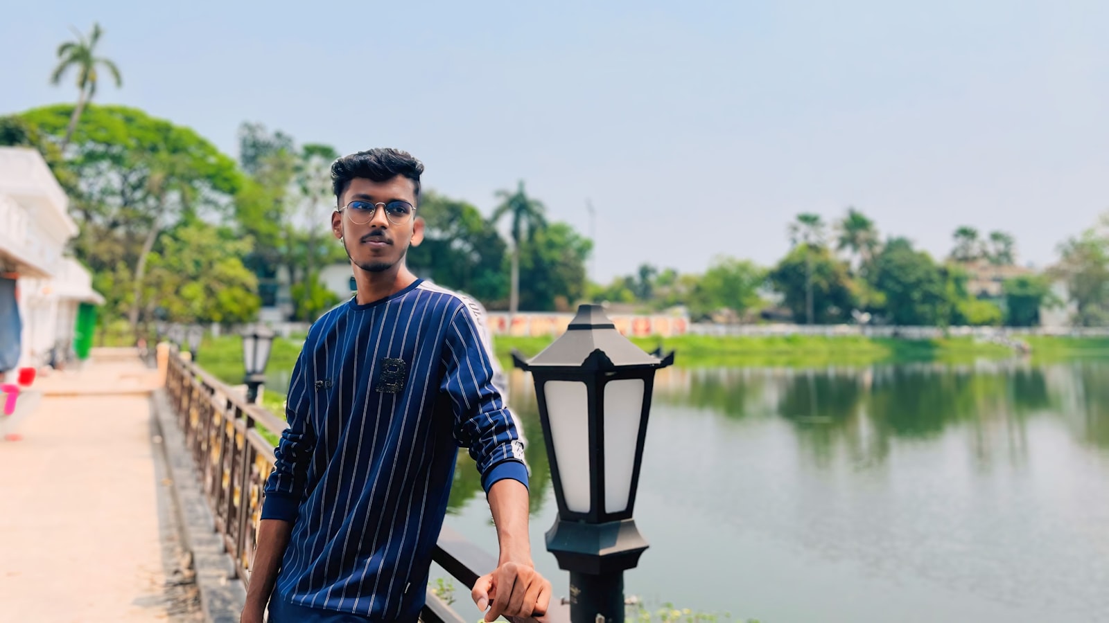 A man standing next to a lamp post near a body of water
