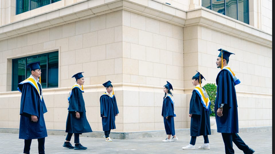 a group of people in blue graduation gowns walking down a street