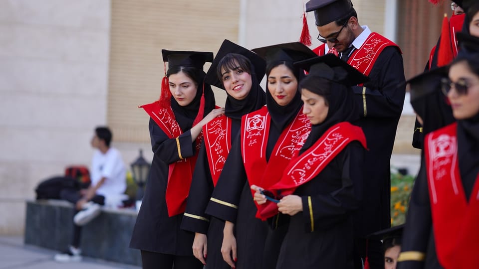 Graduates pose in black gowns and red stoles.