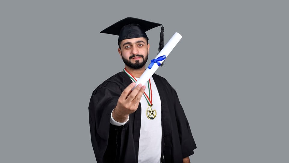 a man wearing a graduation cap and gown holding a diploma