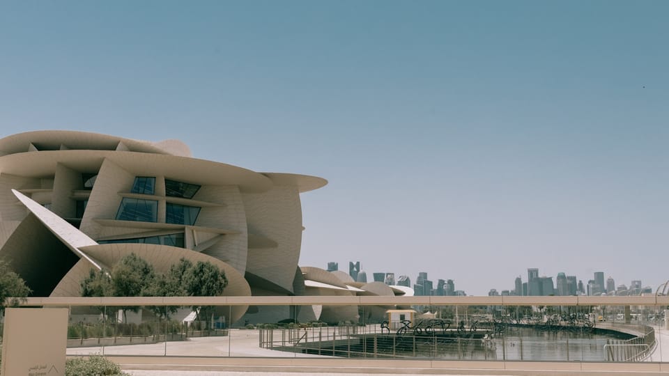 a large building with a curved roof next to a body of water