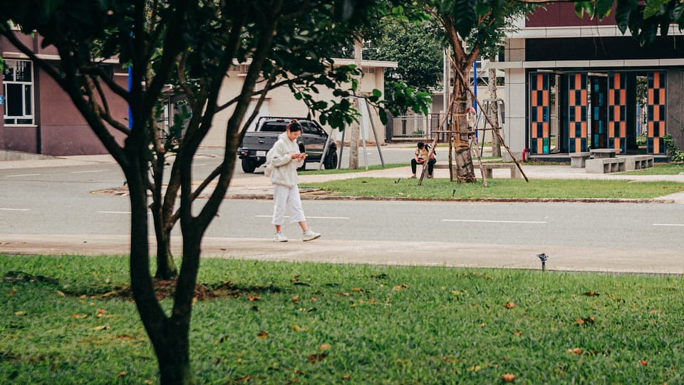 a man walking down a street next to a tree