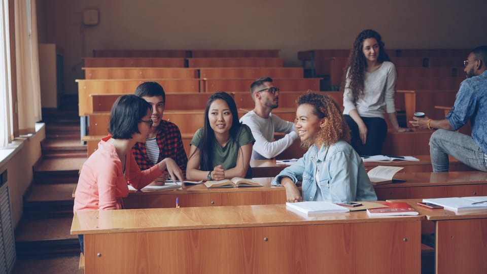 Students talking and studying in a lecture hall.