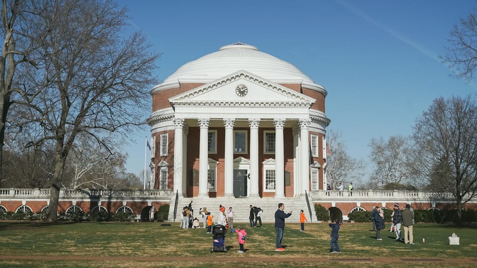 People gather on the lawn of a historic building.