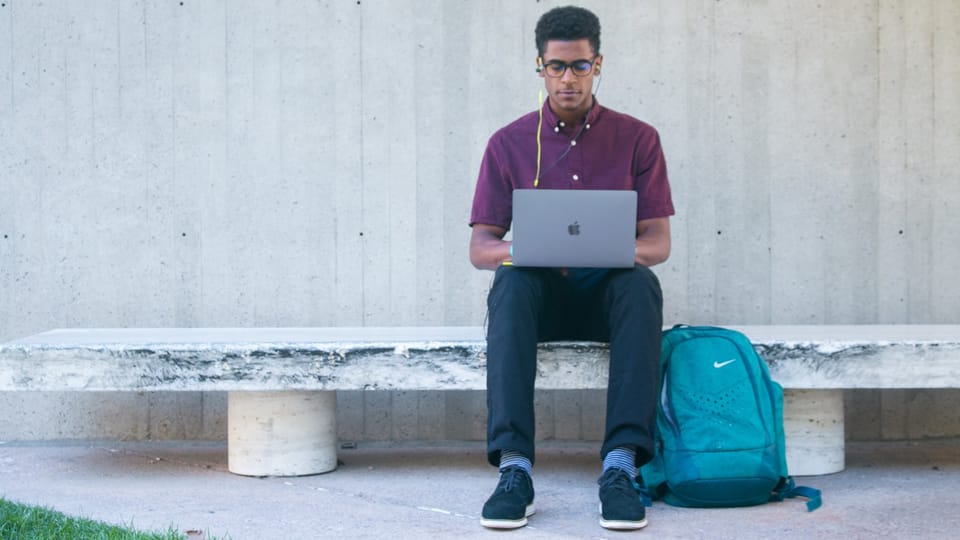 a man sitting on a bench with a laptop