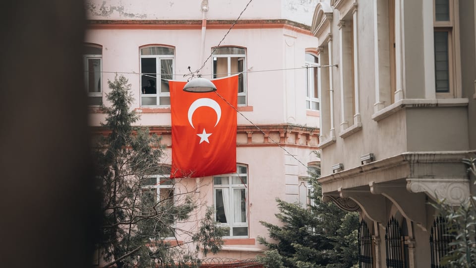 a red flag hanging from a building next to a tree