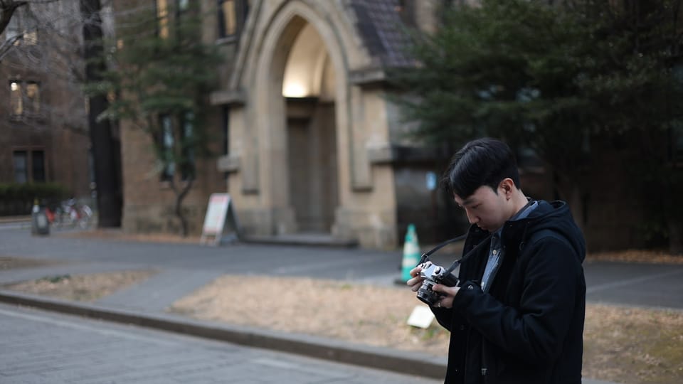 Man holding a camera in front of a building