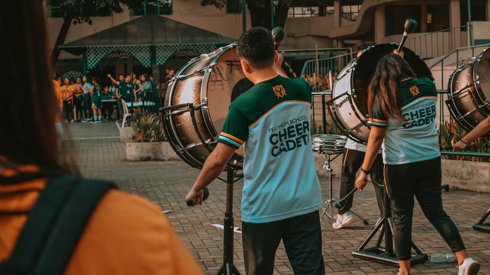 man in green crew neck t-shirt playing drum during daytime