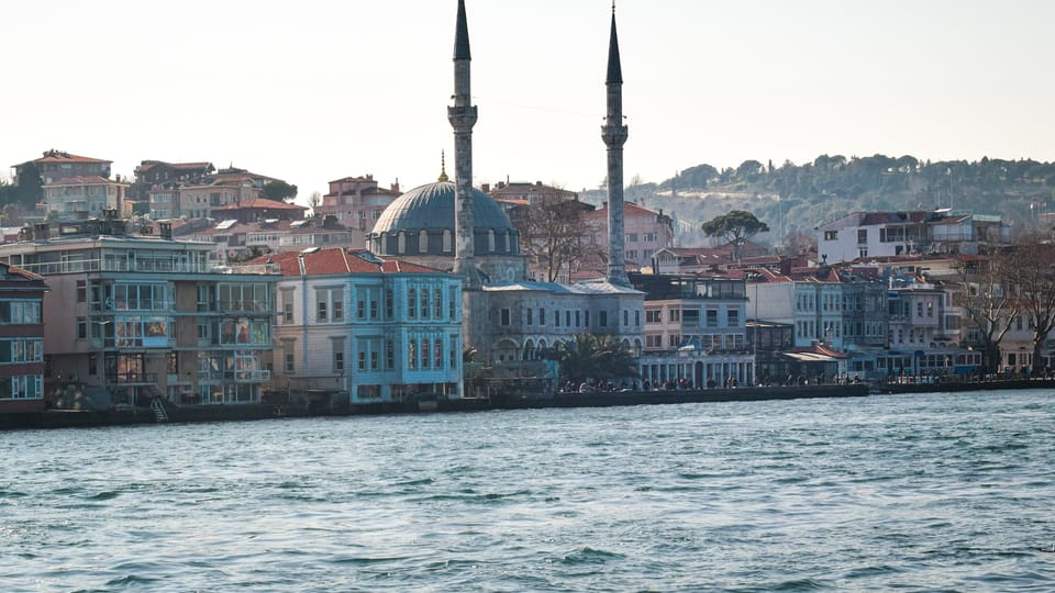 A mosque sits near buildings on the water.