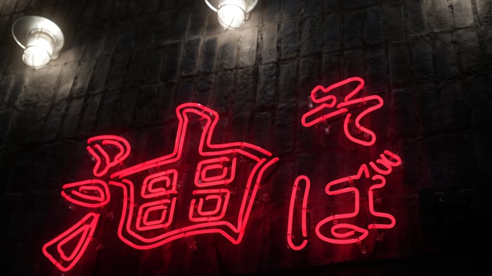 a neon sign with chinese writing on a brick wall