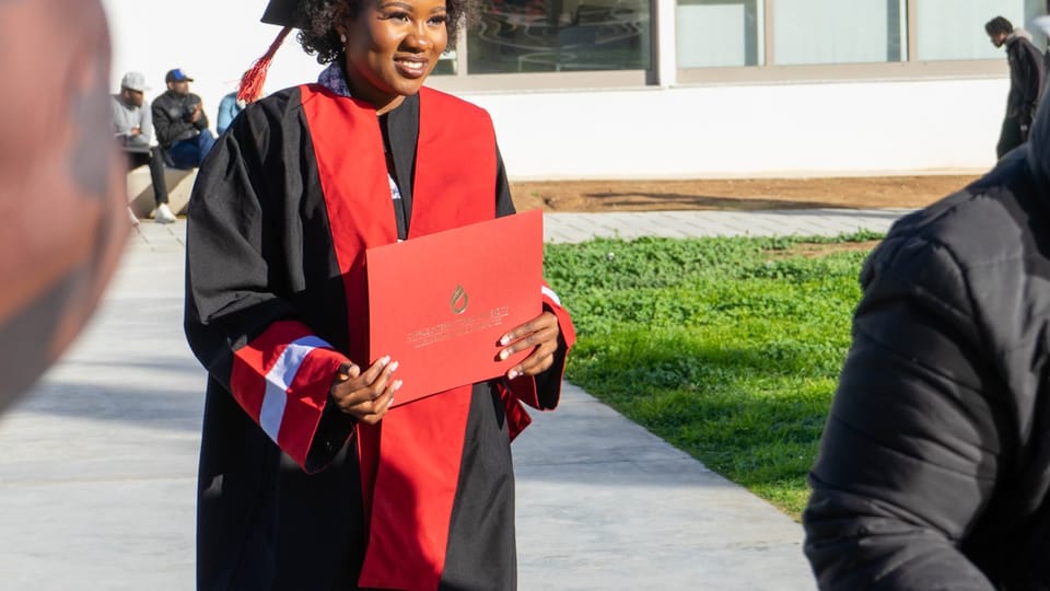 a woman in a graduation gown holding a red piece of paper