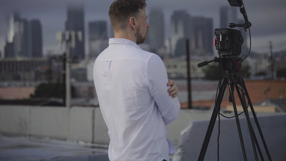 man in white long sleeve shirt standing in front of camera