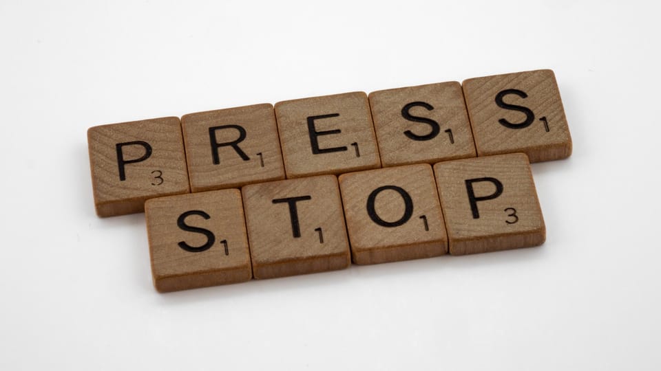 the word press stop spelled with wooden blocks