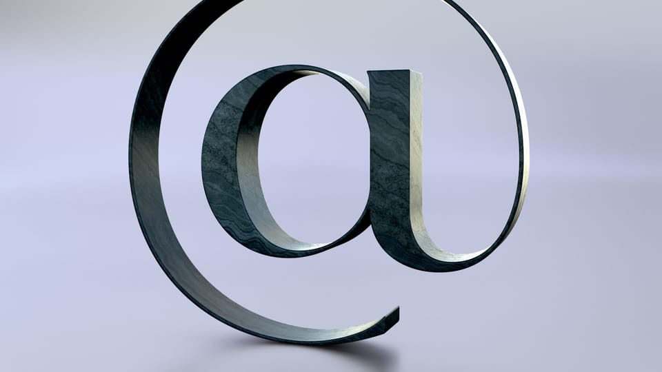 An at symbol is seen on a reflective surface.