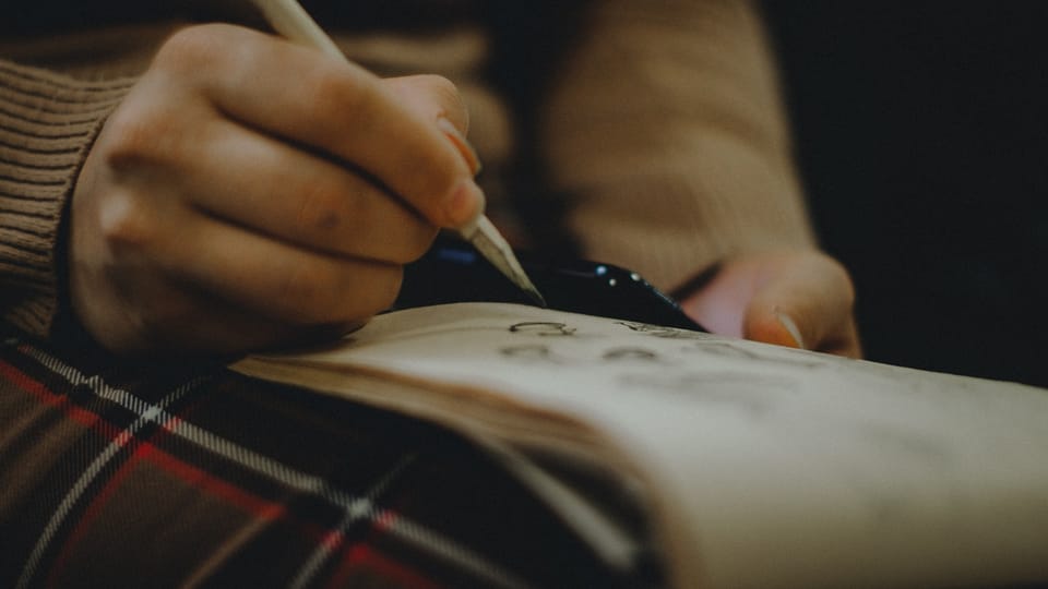 person holding pen and book